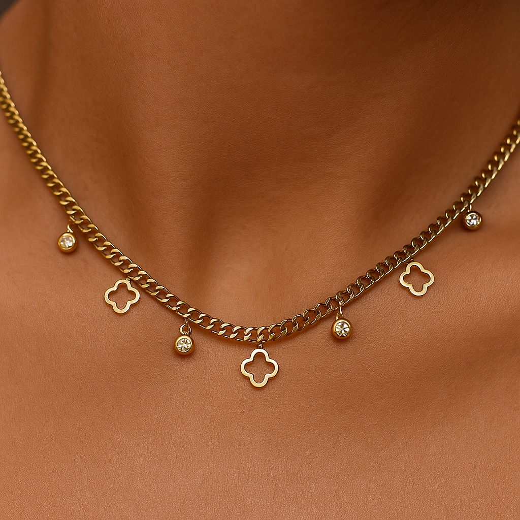 Gold chain necklace with clover-shaped pendants on a brown fabric background