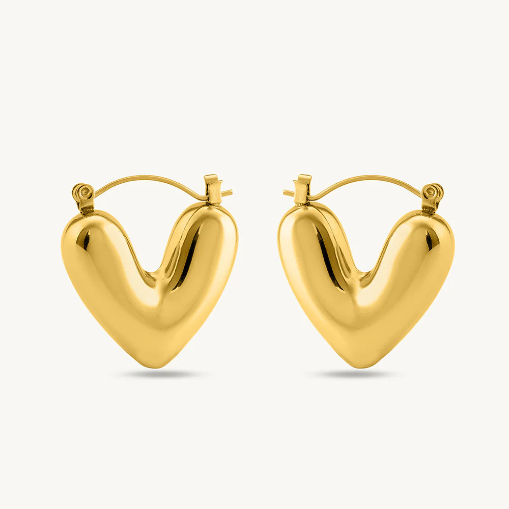 This image features a pair of elegant heart-shaped earrings crafted in 18kt gold. The earrings have a smooth, polished finish that captures the light beautifully, emphasizing their sleek and luxurious design.