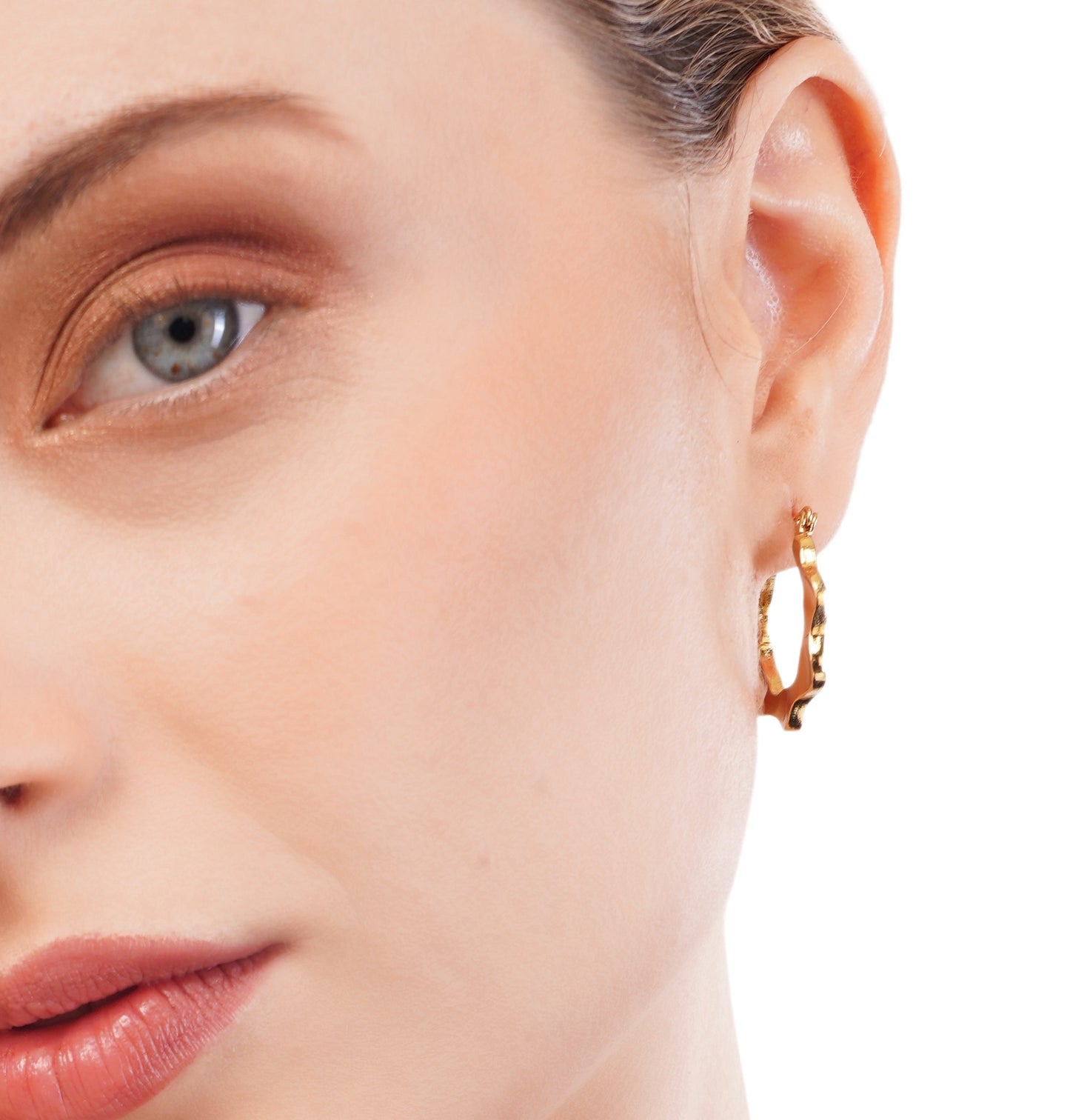 A close-up image of a woman's ear wearing a 18K women's gold hoop earring.