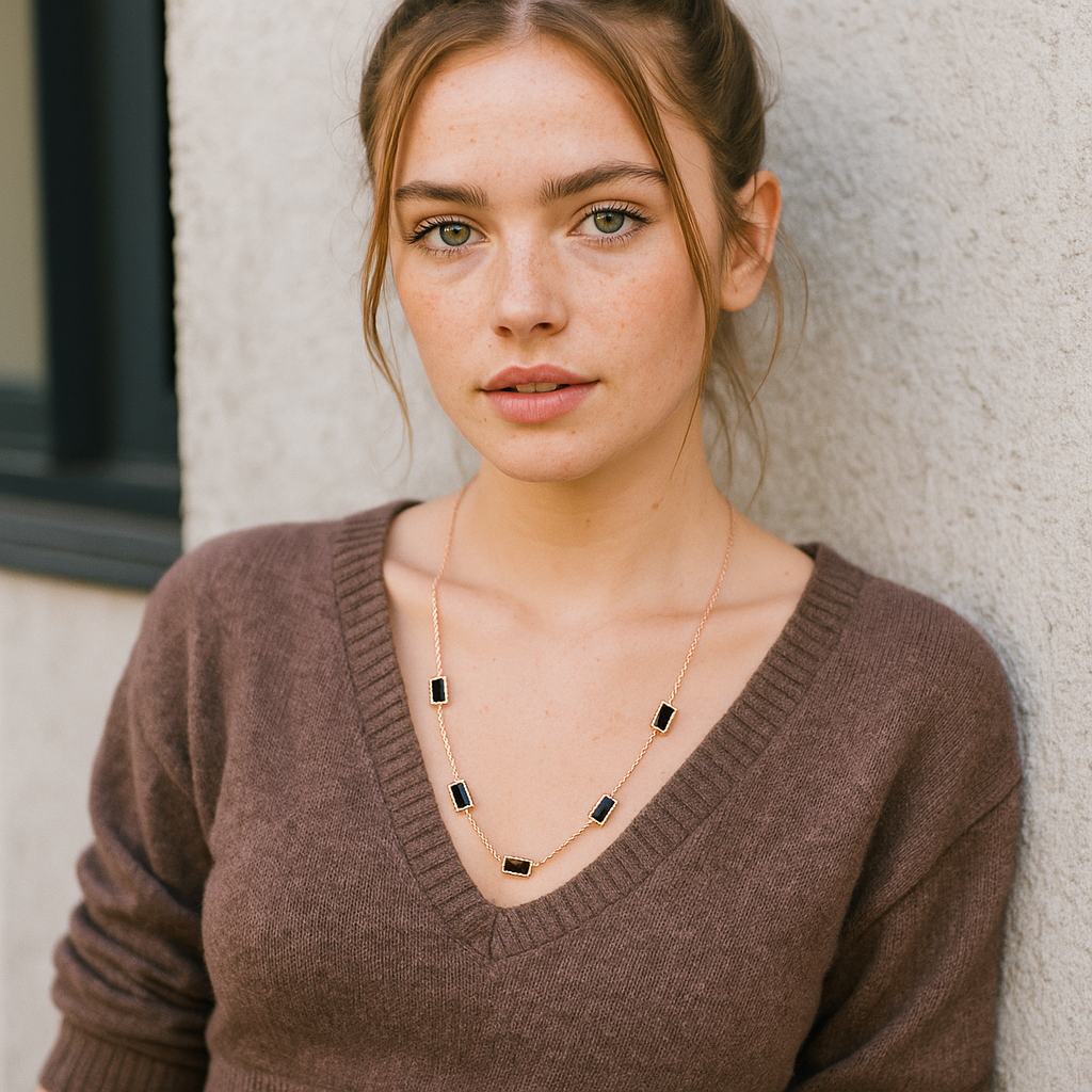 Woman wearing a brown sweater and gold necklace against a neutral background