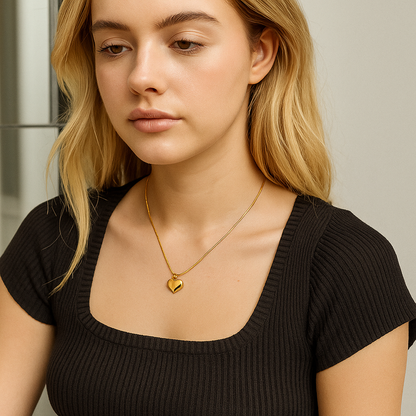 Woman wearing a black top and gold necklace with a heart pendant.