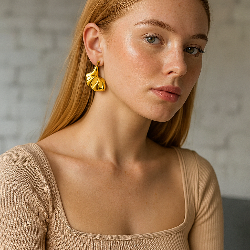 Woman wearing gold earrings with a neutral background