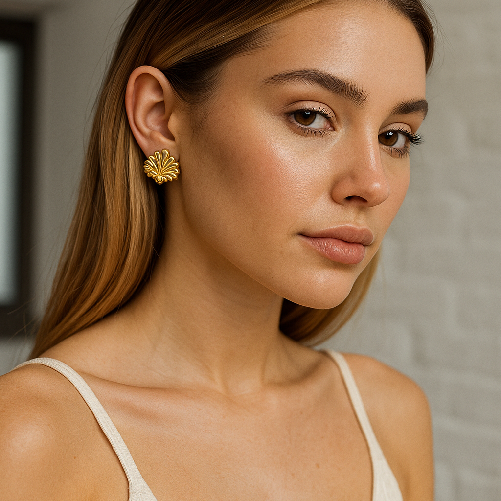 Woman wearing gold earrings with a neutral background