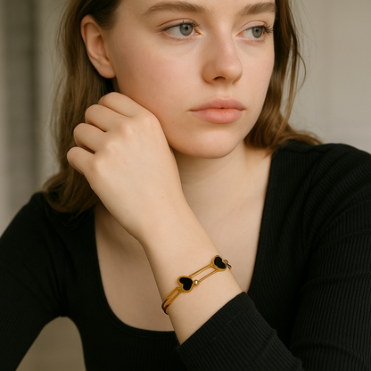 Woman wearing a 18Kt Double Cora Gold Bangle Bracelet with black stones on a neutral background