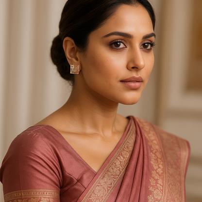 Woman wearing a maroon saree with gold patterns against a neutral background