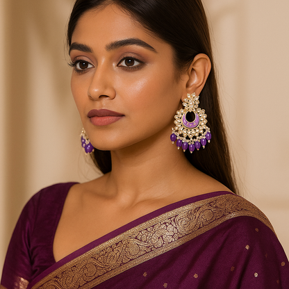Woman wearing a purple saree with gold border and purple Chandbali Indian Traditional earrings against a beige background