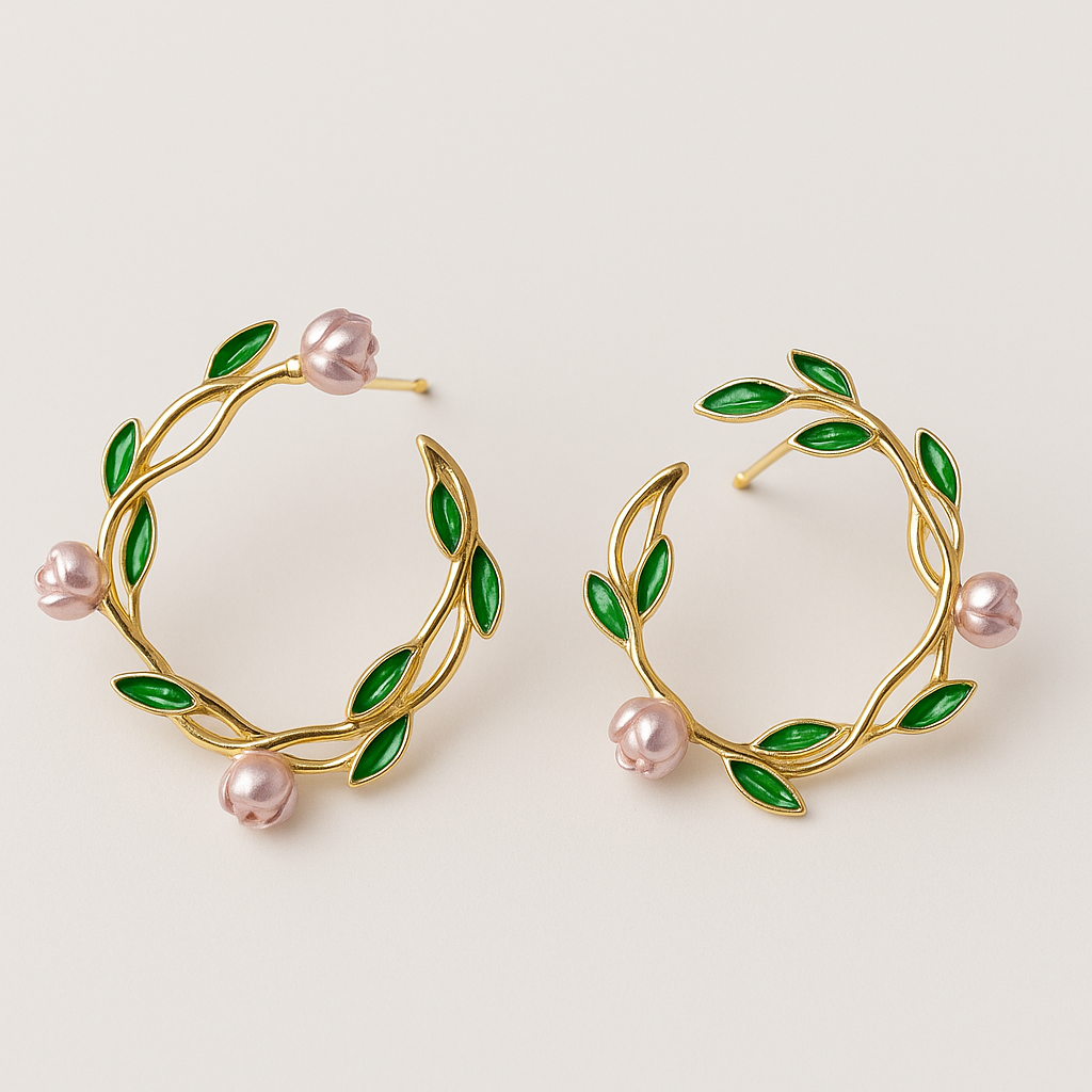 Gold hoop earrings with green leaves and pink pearls on a light beige background
