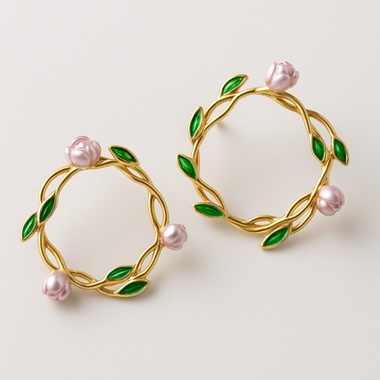 Gold hoop earrings with pink pearls and green leaves on a light background