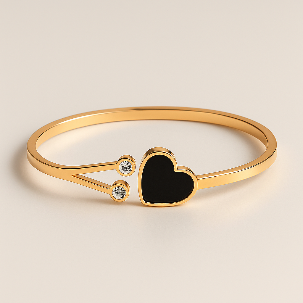 Gold bracelet with a black heart charm on a beige background