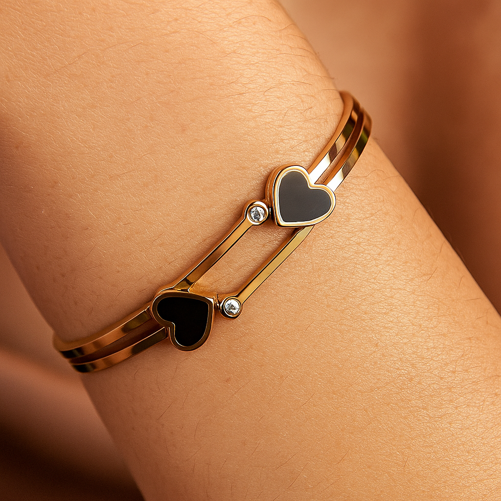 Gold bracelet with heart-shaped charms on a wrist against a neutral background