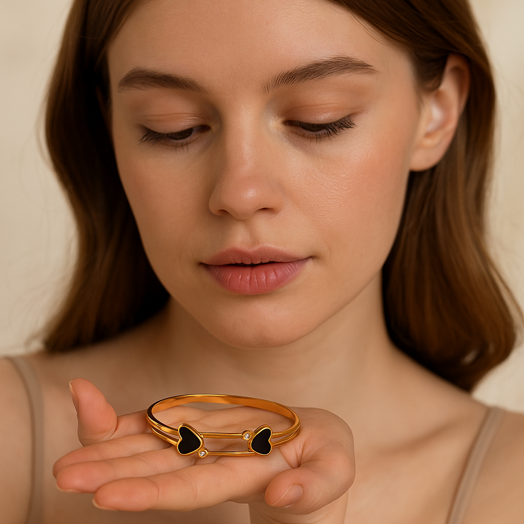 Woman holding a gold ring with heart designs against a neutral background