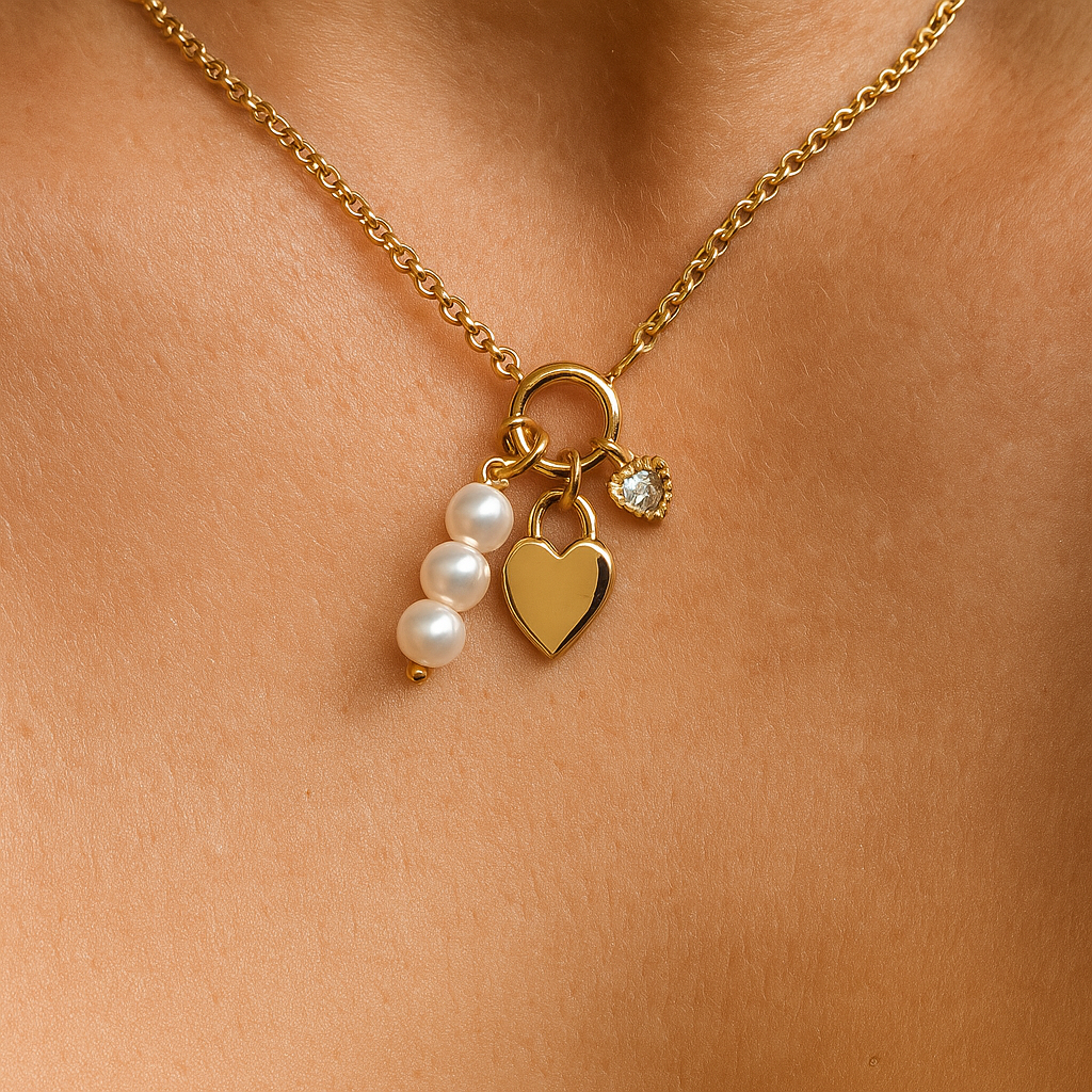 Gold necklace with heart, pearl, and round charm on a person's neck