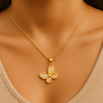 Gold butterfly pendant necklace on a person wearing a beige top