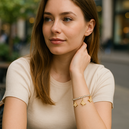 Woman wearing a beige top and gold bracelet with charms outdoors