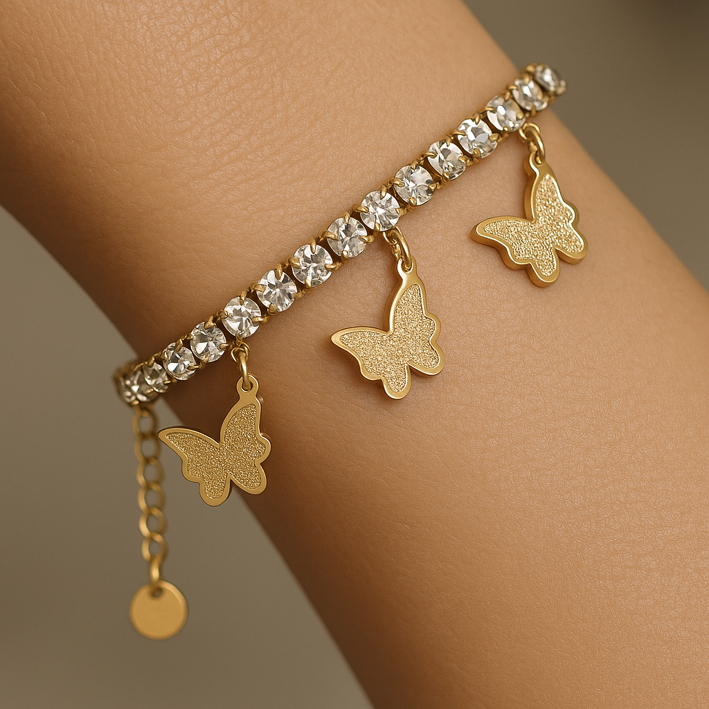 Gold bracelet with butterfly charms on a wrist against a neutral background