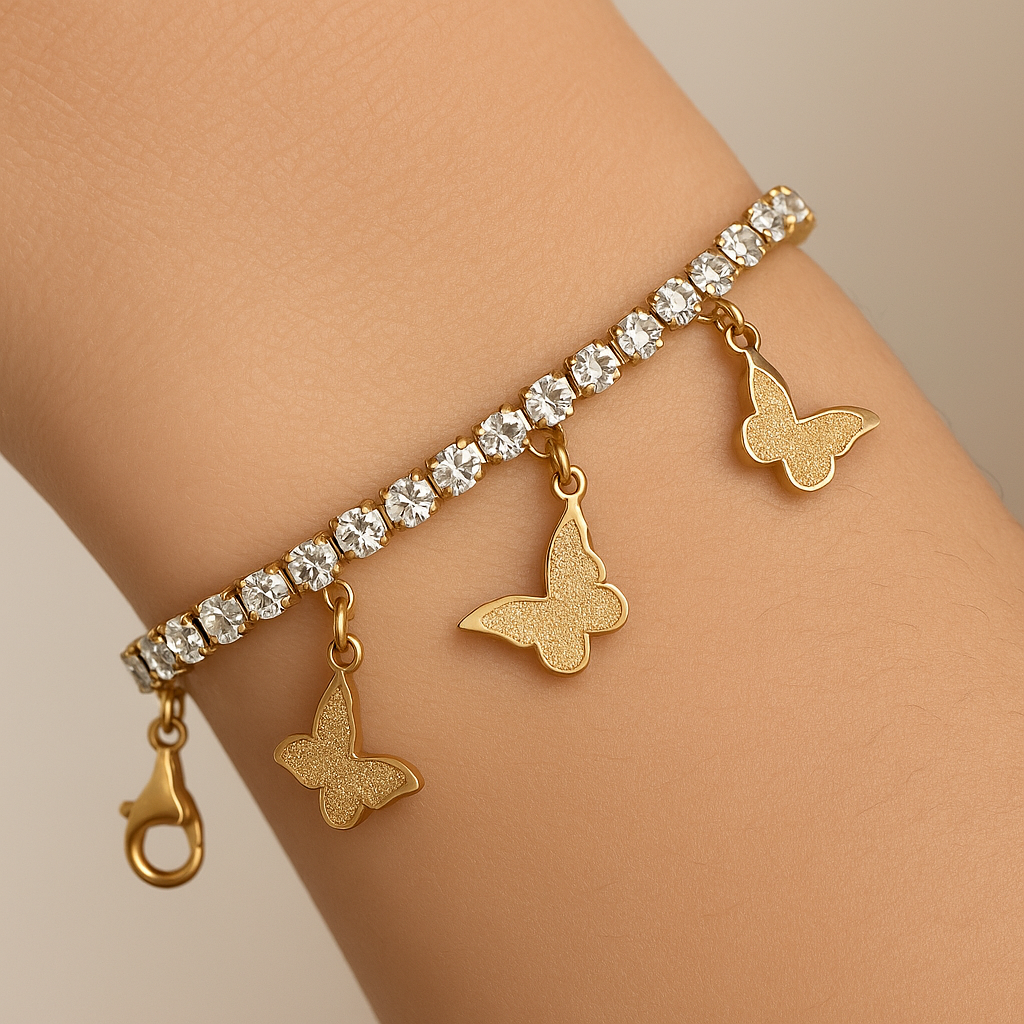 Gold bracelet with butterfly charms and clear stones on a wrist against a neutral background