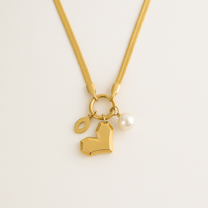 Gold necklace with heart-shaped pendant and pearl on a light beige background