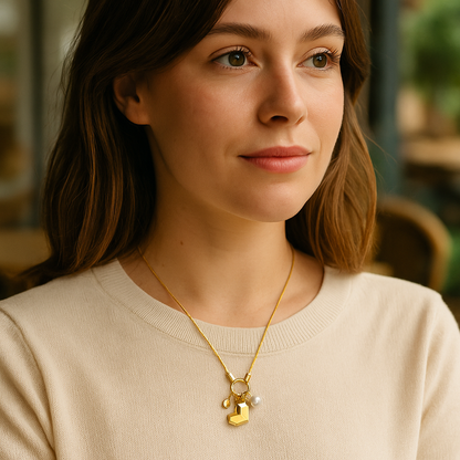 Woman wearing a gold necklace with a lock pendant in a blurred indoor setting