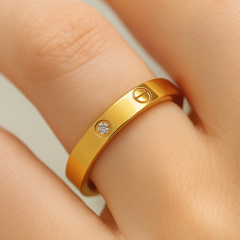 Gold ring with a diamond on a person's finger against a neutral background