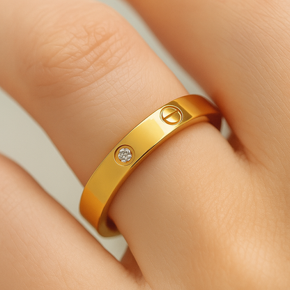 Gold ring with a diamond on a person's finger against a neutral background
