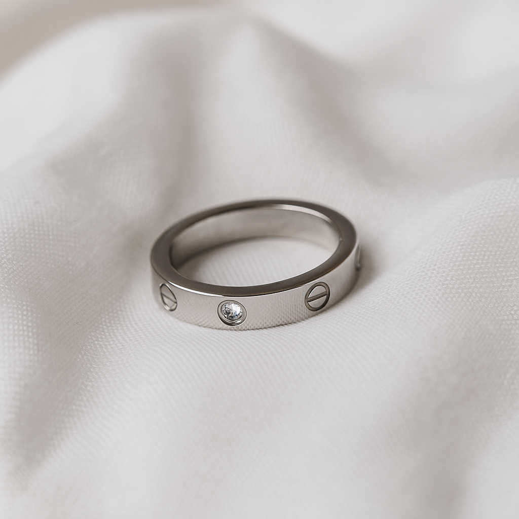 Silver ring with engraved design on a white fabric background