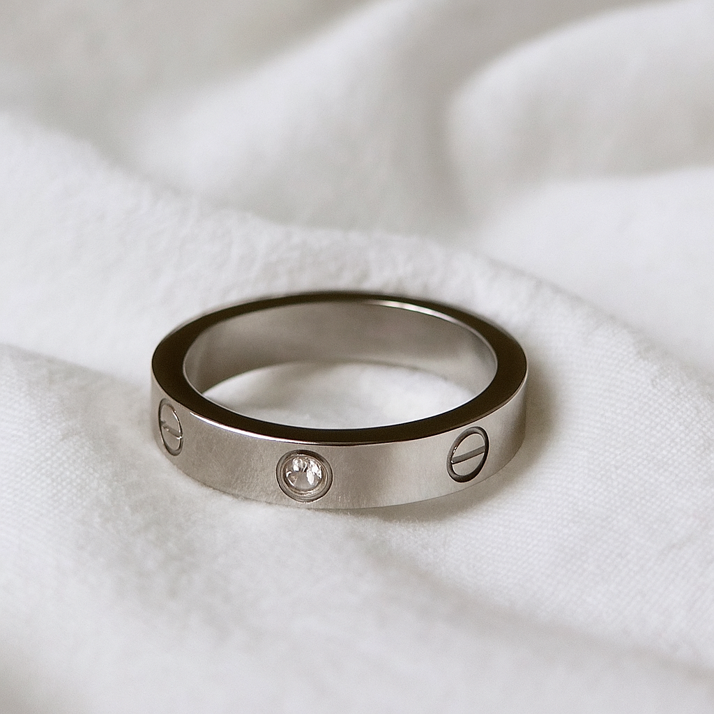 Silver ring with engraved designs on a white fabric background
