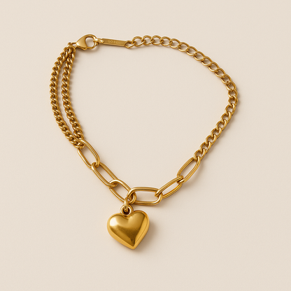 Gold chain bracelet with a heart-shaped pendant on a beige background
