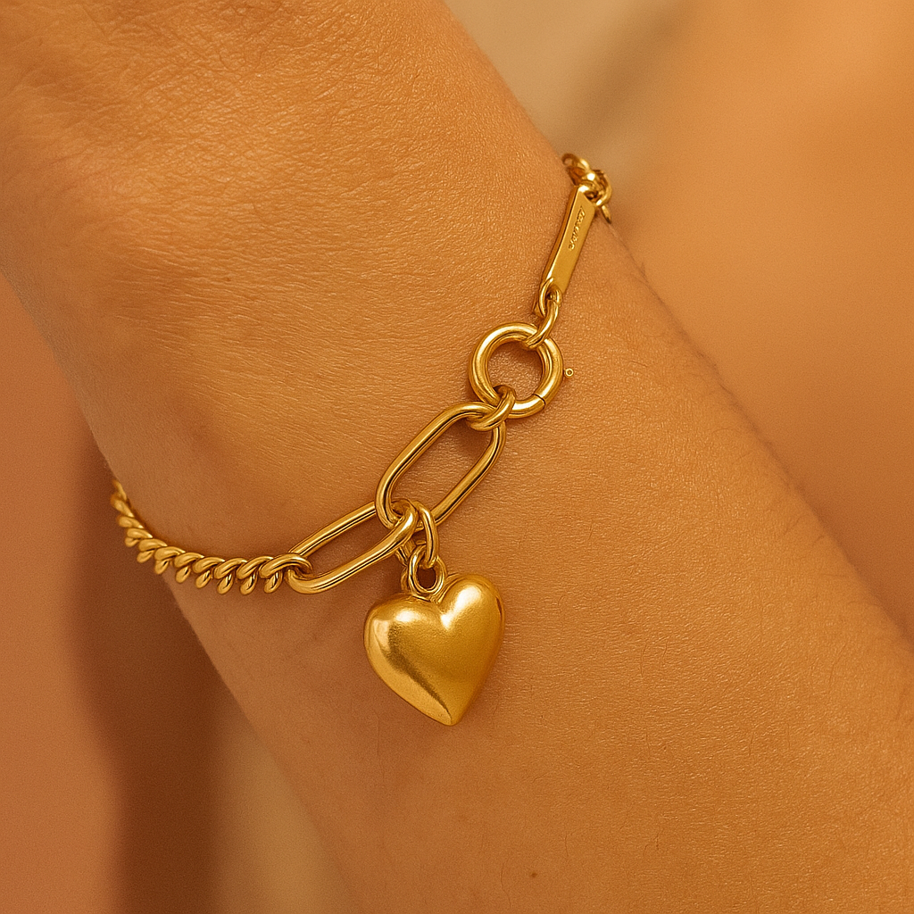 Gold bracelet with a heart charm on a person's wrist against a matching background