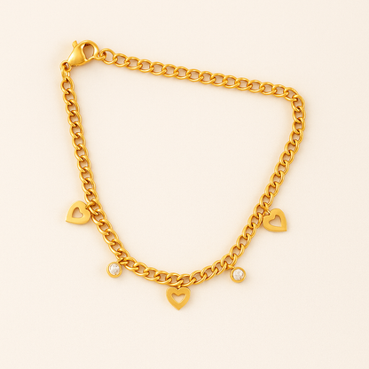 Gold chain bracelet with heart-shaped charms on a light beige background