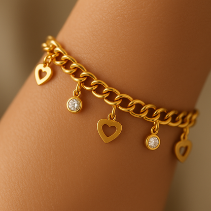 Gold chain bracelet with heart-shaped charms on a wrist against a neutral background
