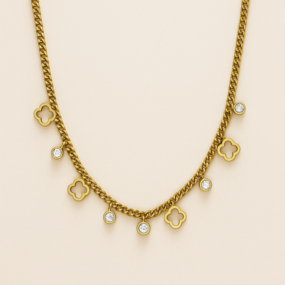 Gold chain necklace with clover and diamond-like pendants on a beige background