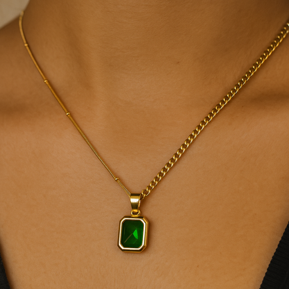 Gold necklace with a green gemstone pendant on a person's neck.