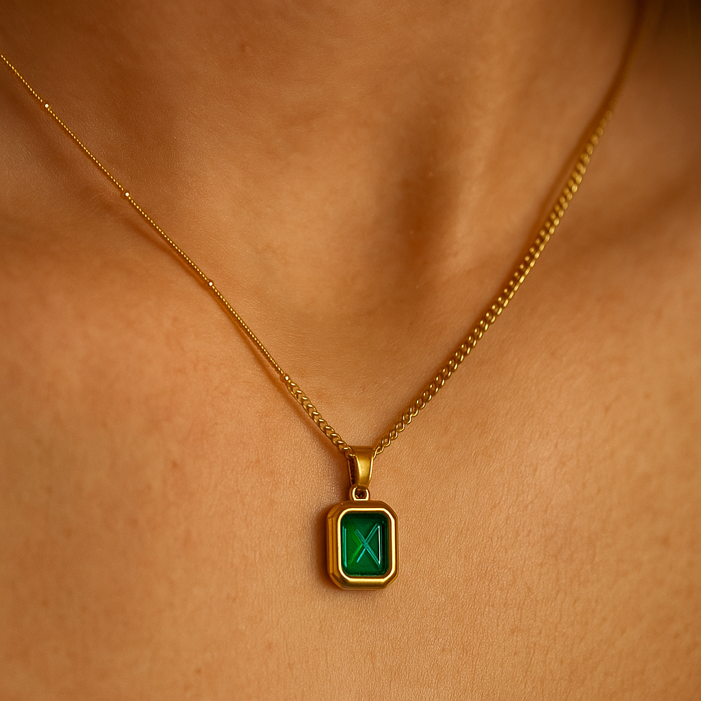 Gold necklace with a green gemstone pendant on a person's neck