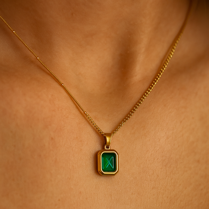 Gold necklace with a green gemstone pendant on a person's neck