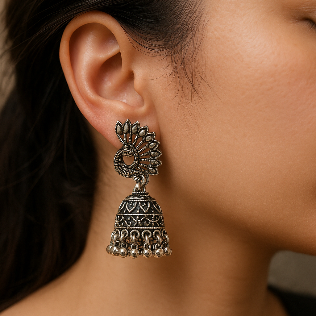 Close-up of a person wearing an ornate silver earring with dangling elements.