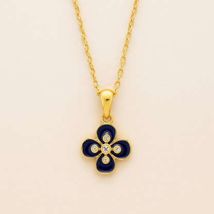 Gold necklace with a blue clover-shaped pendant on a beige background