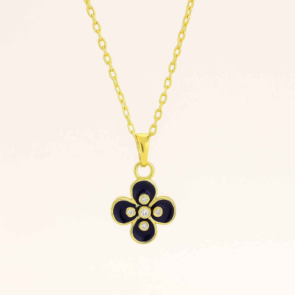 Gold necklace with a black flower pendant on a beige background