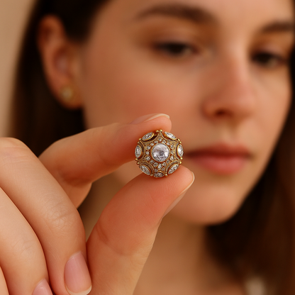 Close-up of a woman holding a decorative earring with intricate design.