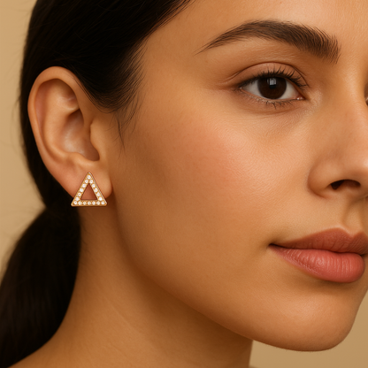 Close-up of a woman wearing a triangle-shaped earring against a beige background