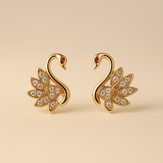 Gold swan earrings with gemstones on a beige background