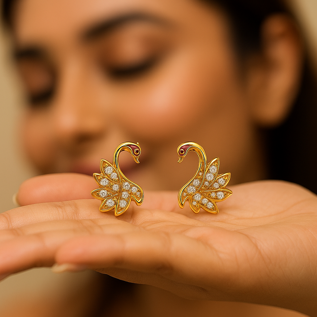 Gold swan earrings with diamond details held in a hand against a blurred background