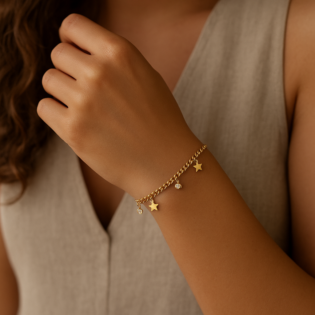 Gold bracelet with star charms on a person's wrist against a neutral background