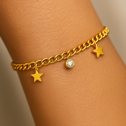 Gold chain bracelet with star and round charm on a wrist against a neutral background