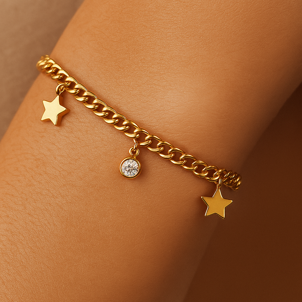 Gold chain bracelet with star and round charm on a wrist against a brown background