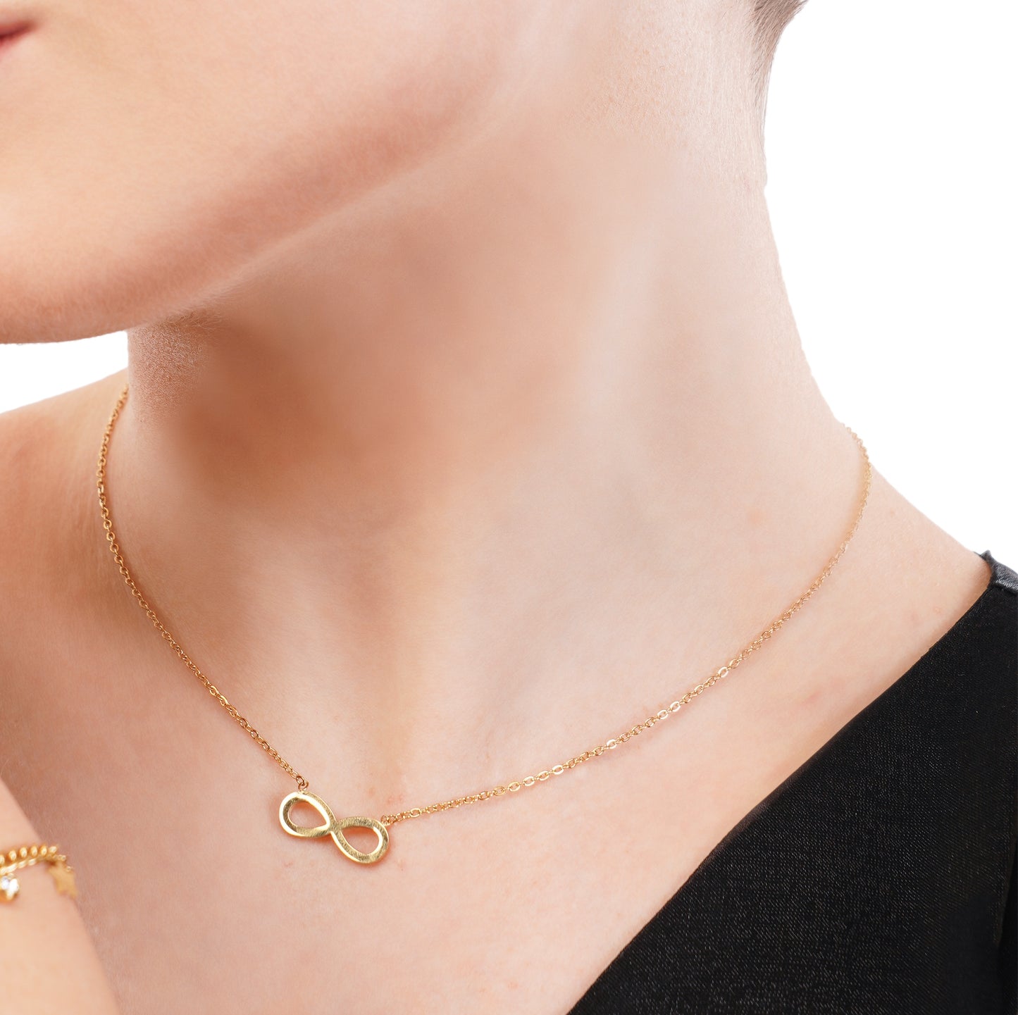 A close-up image of a woman wearing an 18Kt gold infinity chain pendant necklace.