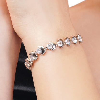 Silver bracelet with clear stones on a person's wrist against a neutral background