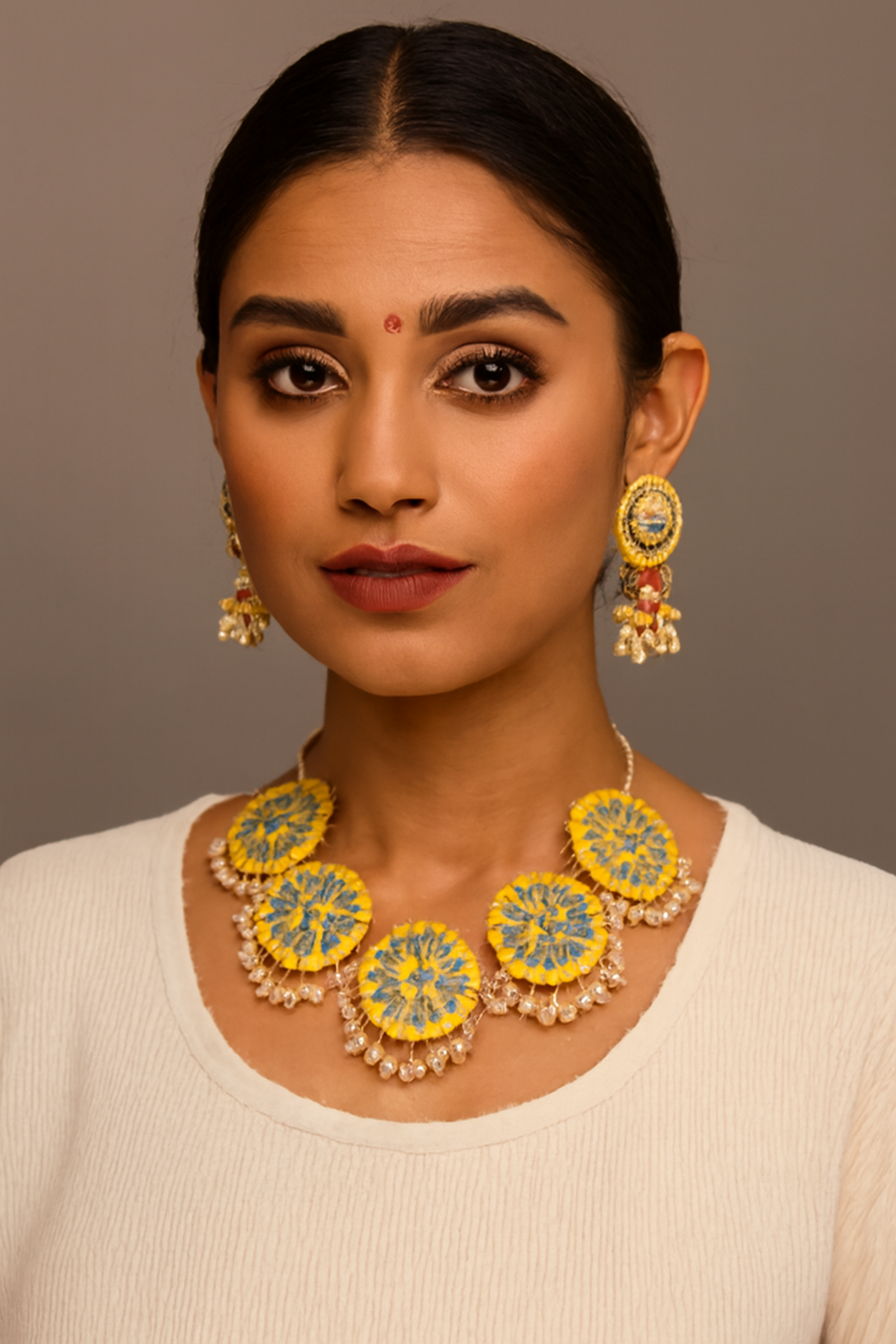 Woman wearing a yellow and green floral necklace and earrings against a brown background