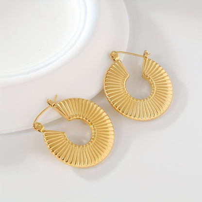 A pair of 18K gold hoop earrings with a striped texture, displayed on a white surface.
