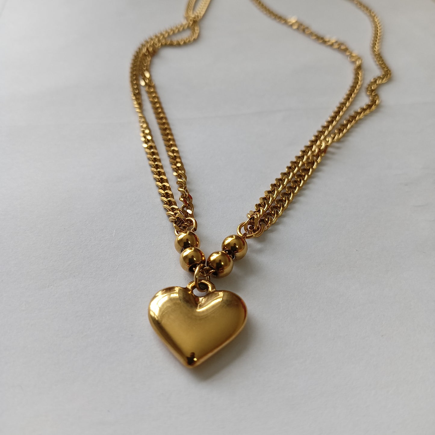 Gold heart-shaped pendant necklace on a light gray background