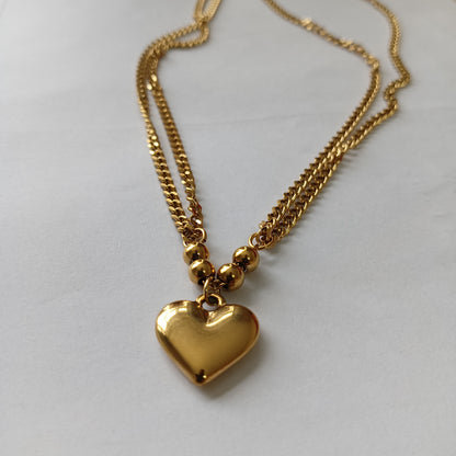 Gold heart-shaped pendant necklace on a light gray background